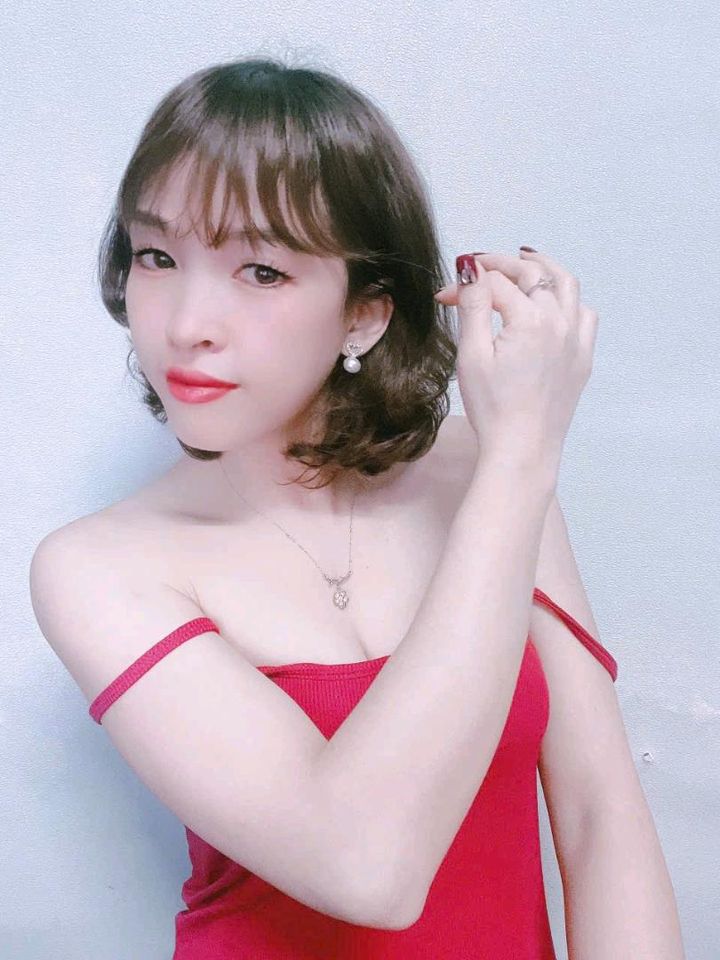 Woman with a short bob in a red dress posing for a video chat