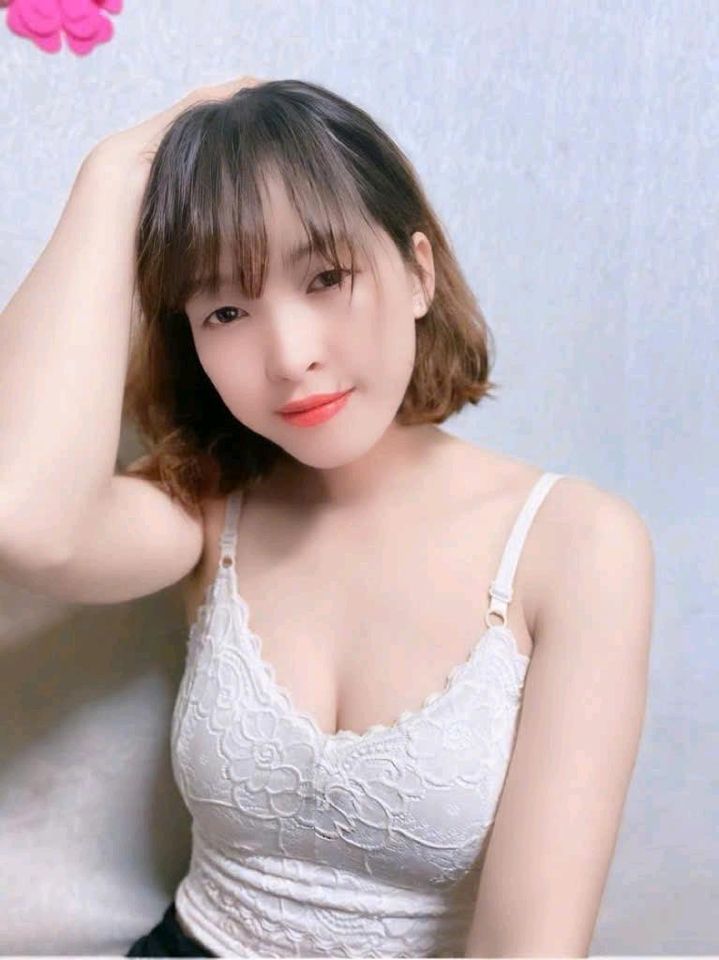 Young woman with a bob haircut in a white top smiling at the camera